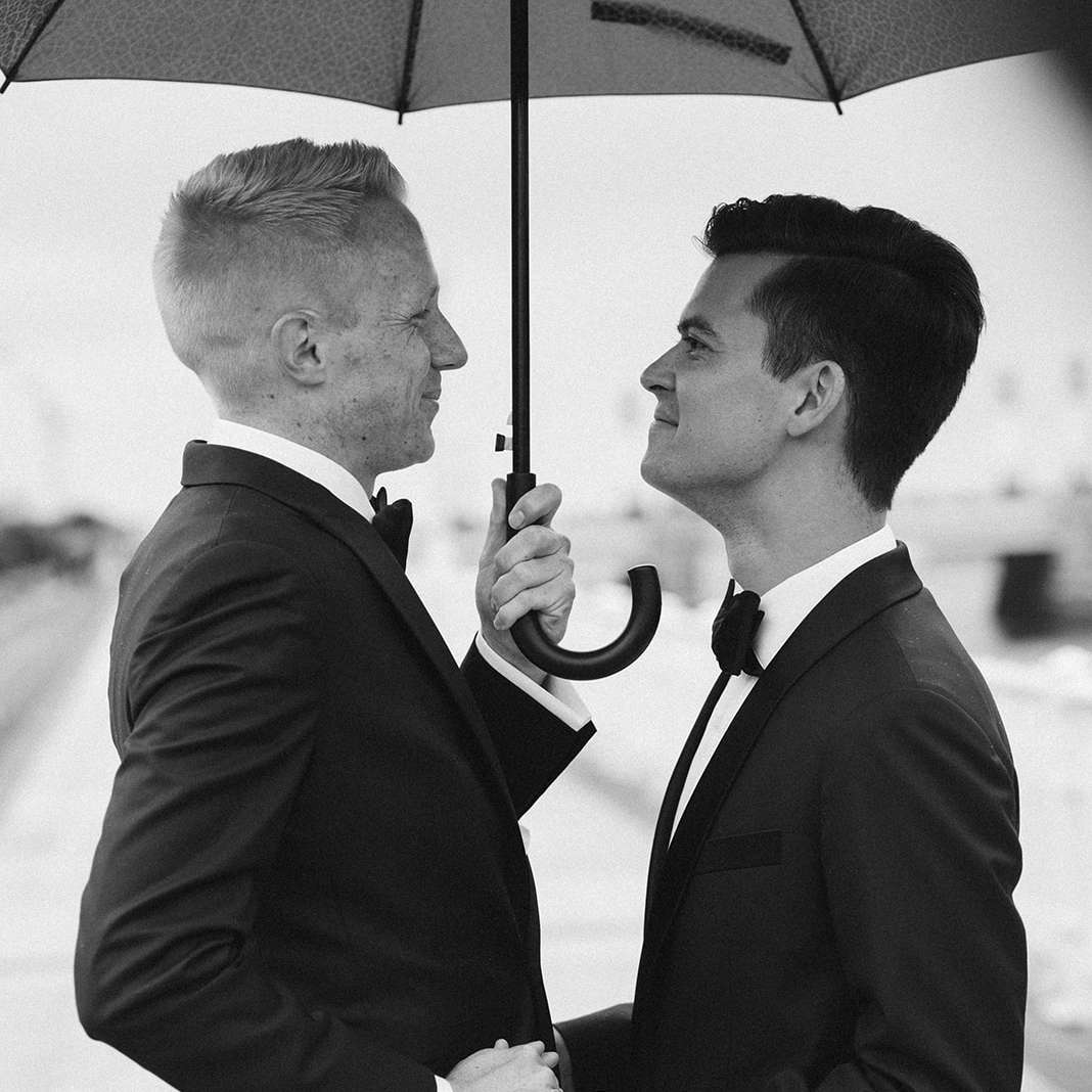 握手和分享伞的两个新郎