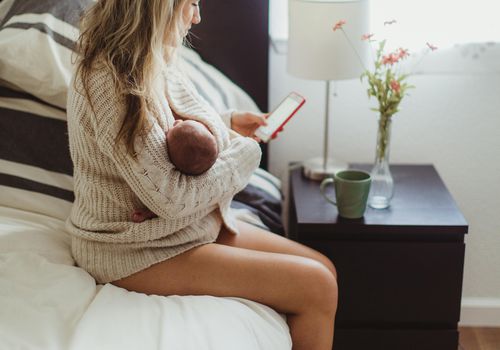 一个抱着新生儿坐在床上的女人