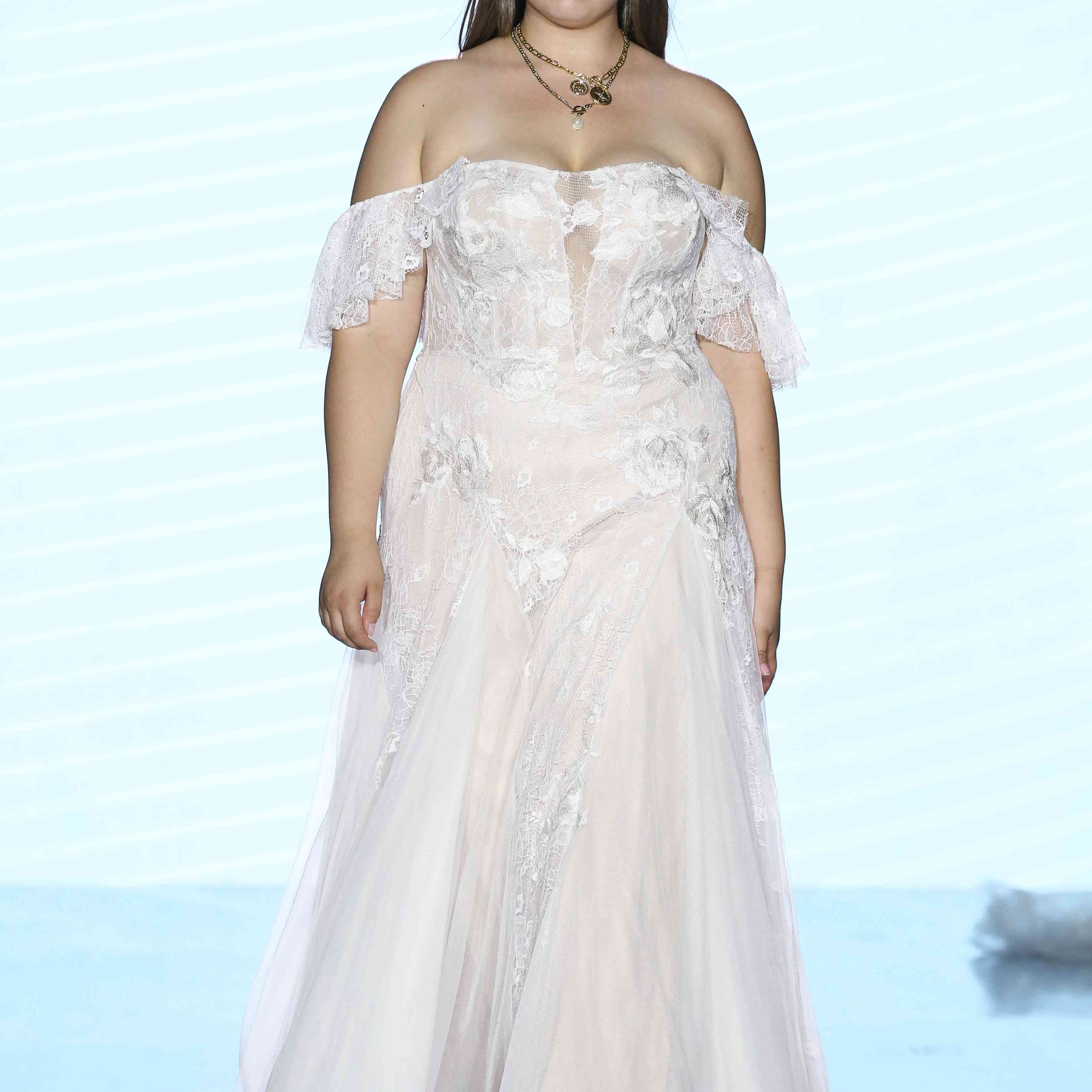模特在露肩薄纱的蕾丝结婚礼服与透明低领