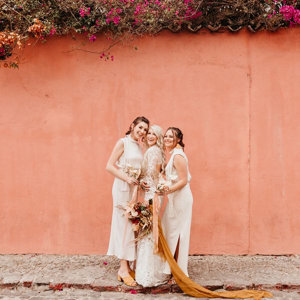 摆在桃红色墙壁前面的新娘和伴娘