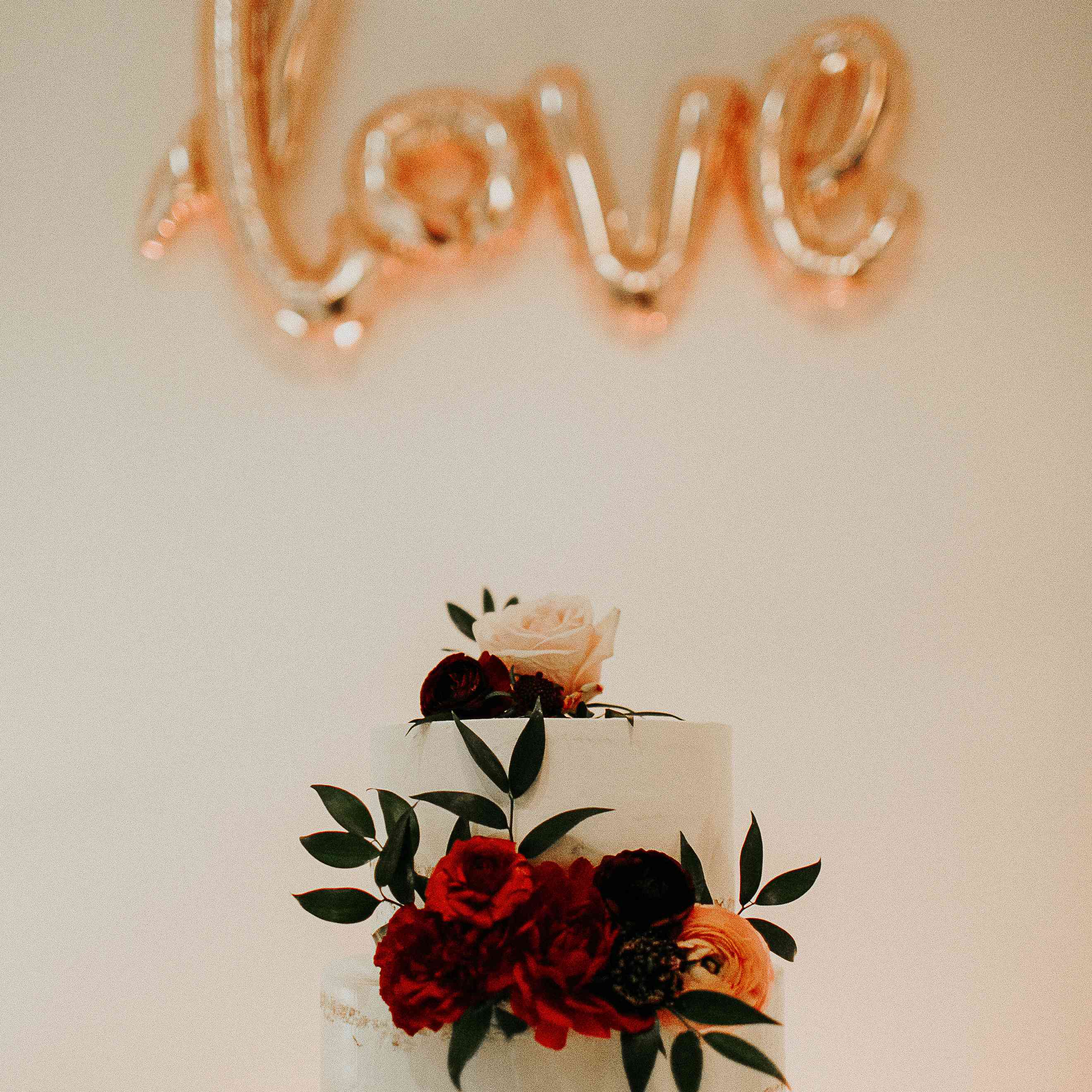 带有红色花朵的两层裸体婚礼蛋糕