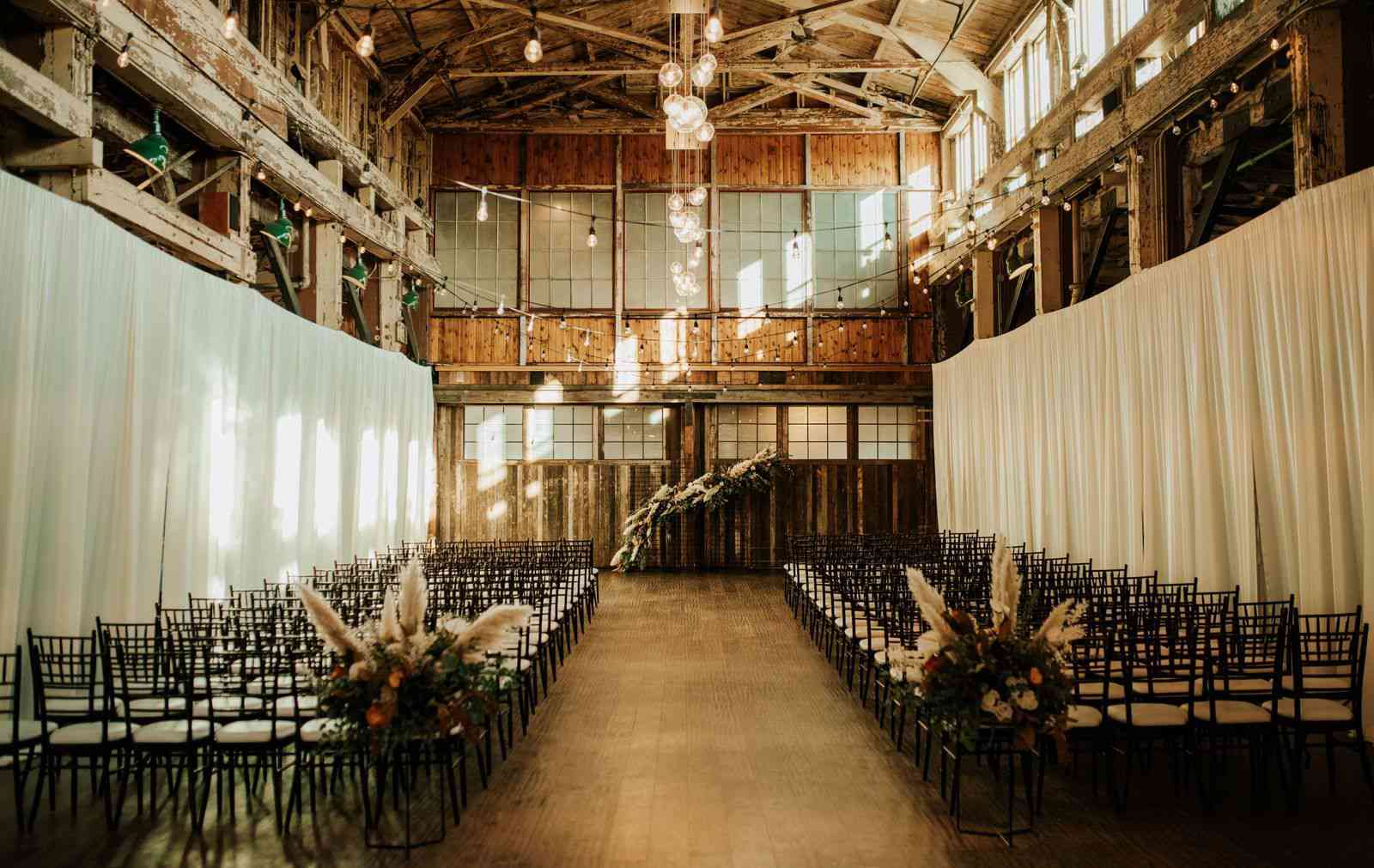 一个室内仪式，在过道的开始，搭配花卉设施，以匹配拱形背景