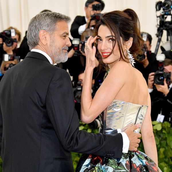 乔治·克鲁尼把手放在妻子的小妻子的背上，因为她微笑着刷一缕头发。