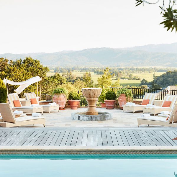 一个男人和一个女人沿着游泳池甲板散步，背景是葡萄园