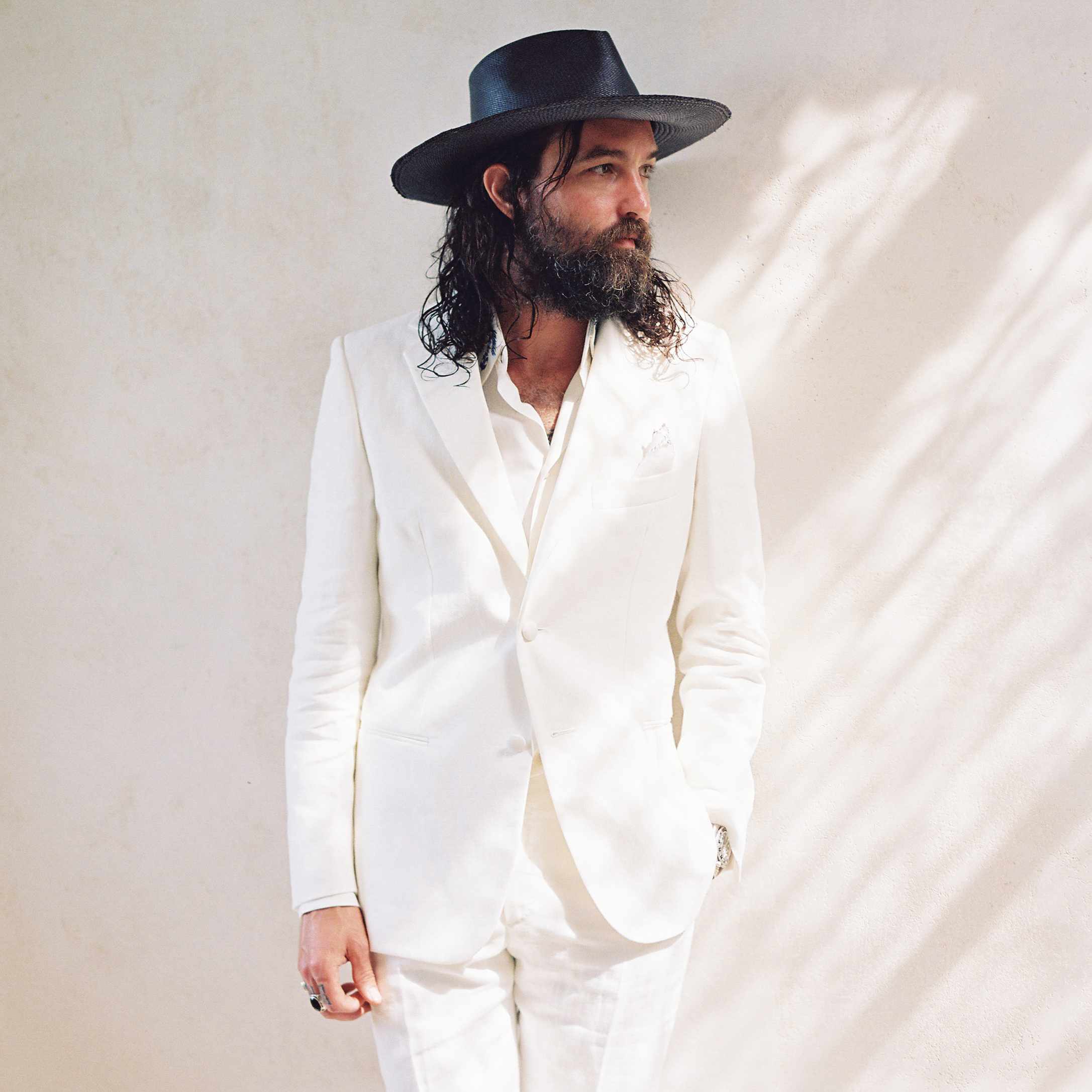 新郎穿一身白色的西装，戴帽子，留胡子，长发