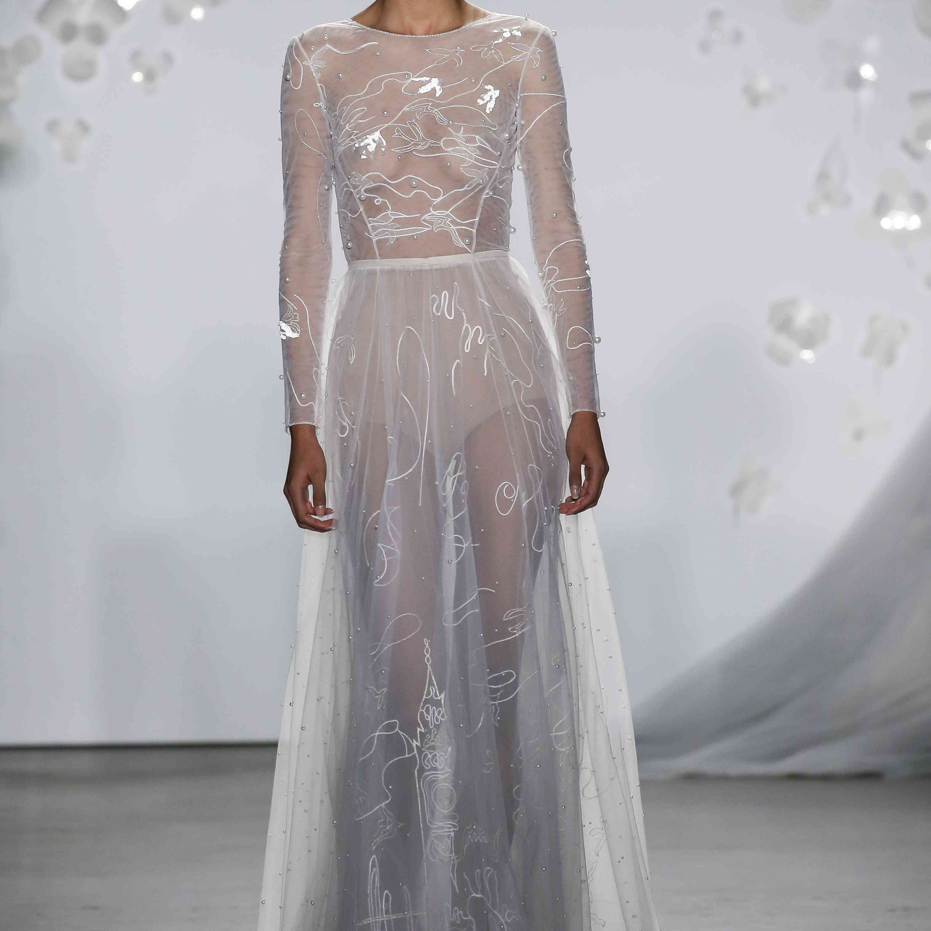 模特在透明长袖拖地礼服与闪闪发光的刺绣