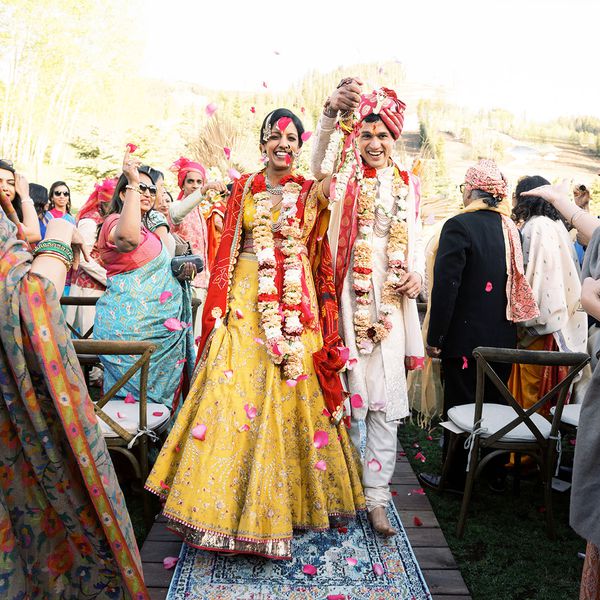 新娘和新郎手牵着手”class=