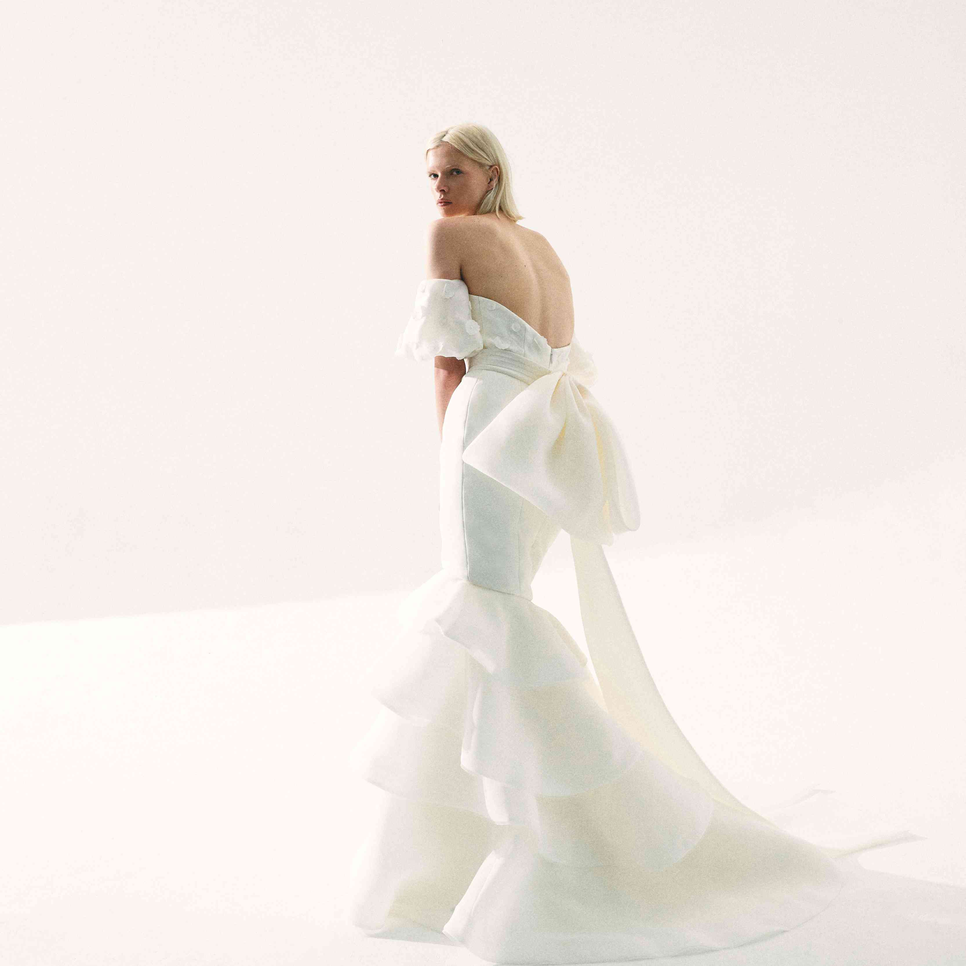 模型场外的肩美人鱼礼服与分层裙子和大蝴蝶结在后面详细