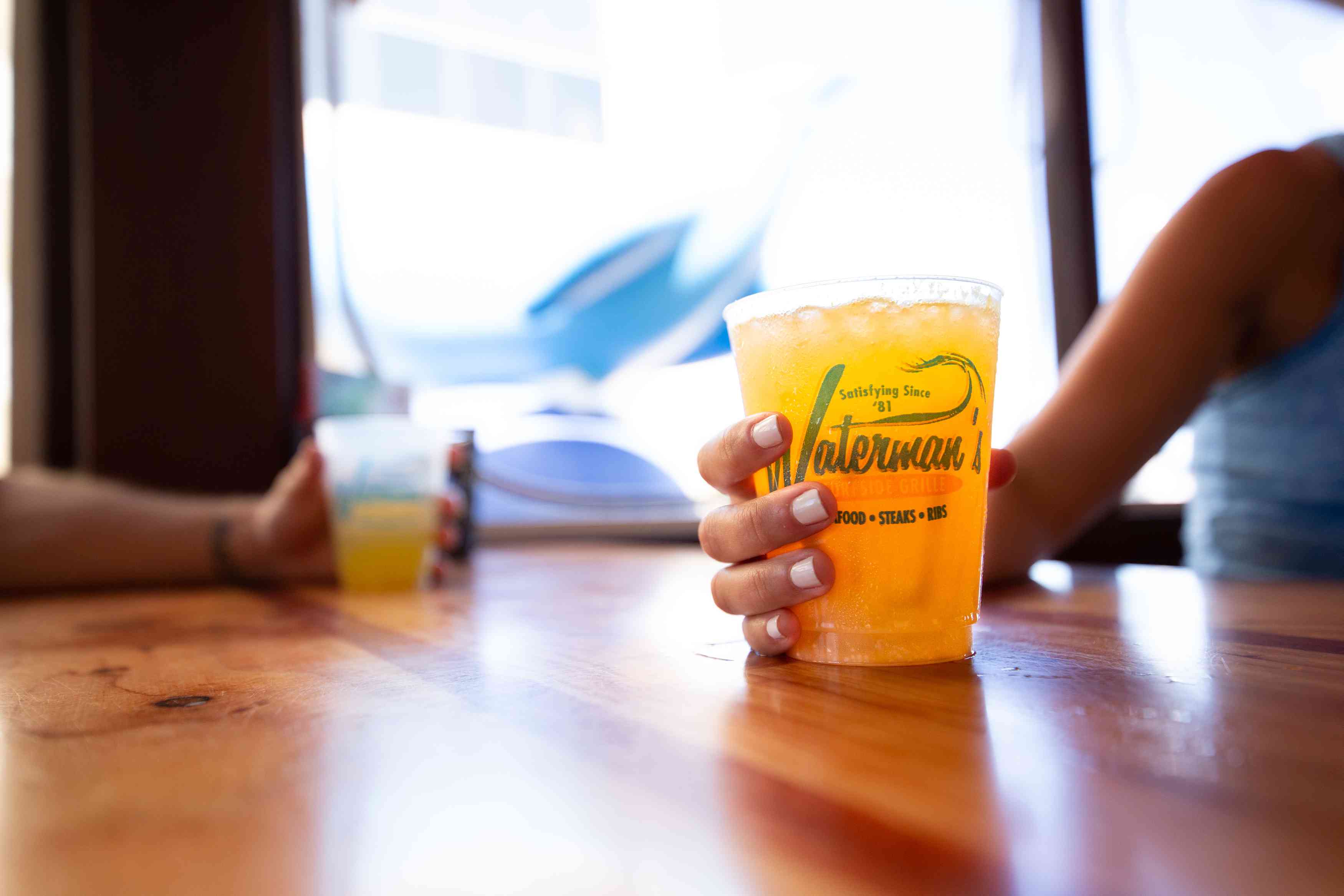 女人拿着桔子粉碎在沃特曼还为海边格栅的鸡尾酒