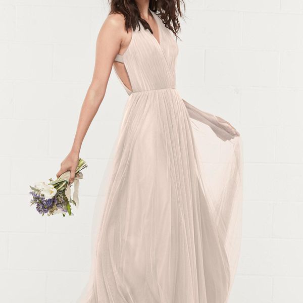 女人穿着飘逸的米色连衣裙，手持花束