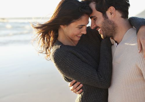 微笑和拥抱在海滩的男人和妇女
