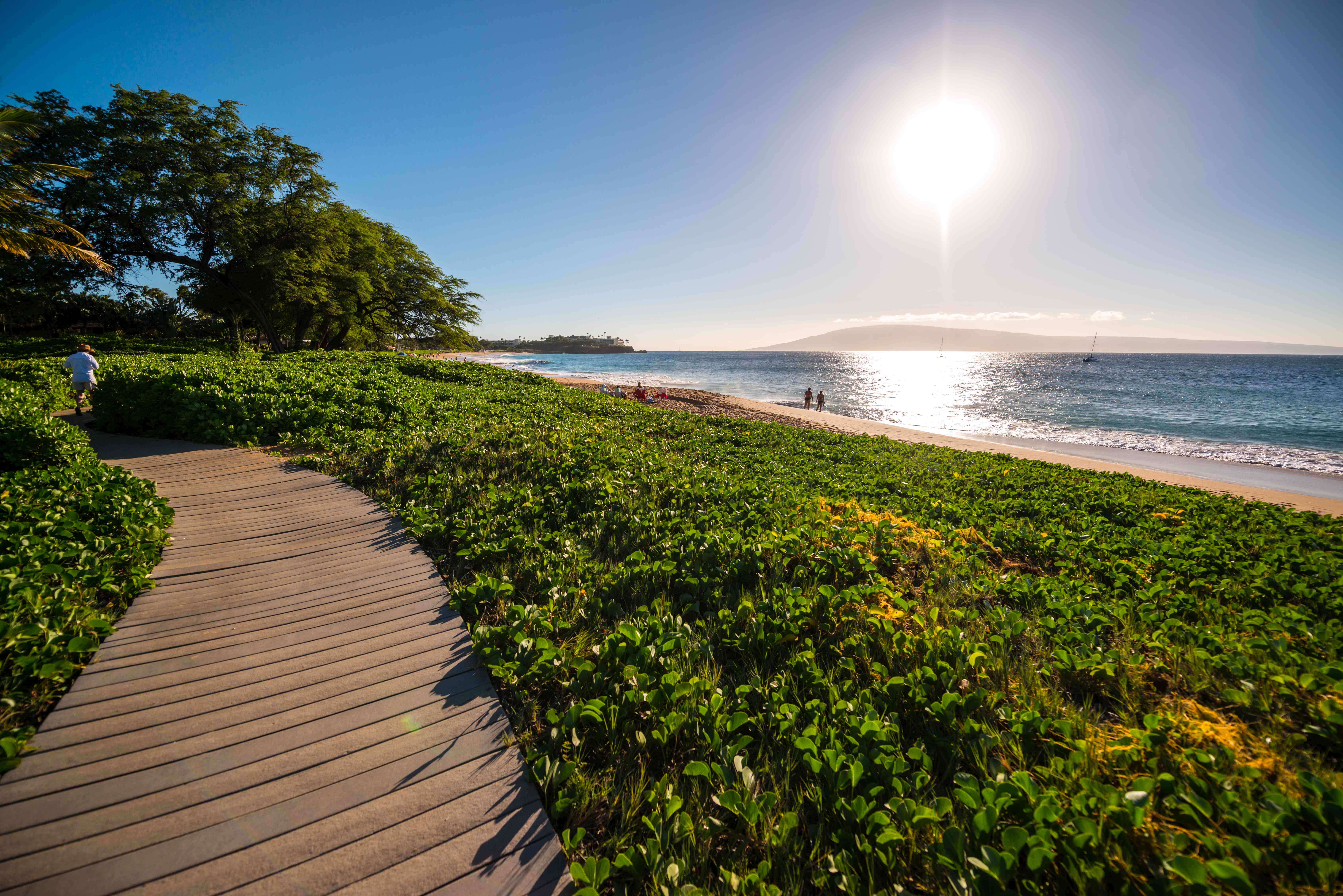 人们走在夏威夷毛伊岛的卡那帕利海滩的木板路和海滩上