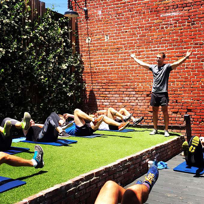 人们在草坪上做AB锻炼，而教练指导