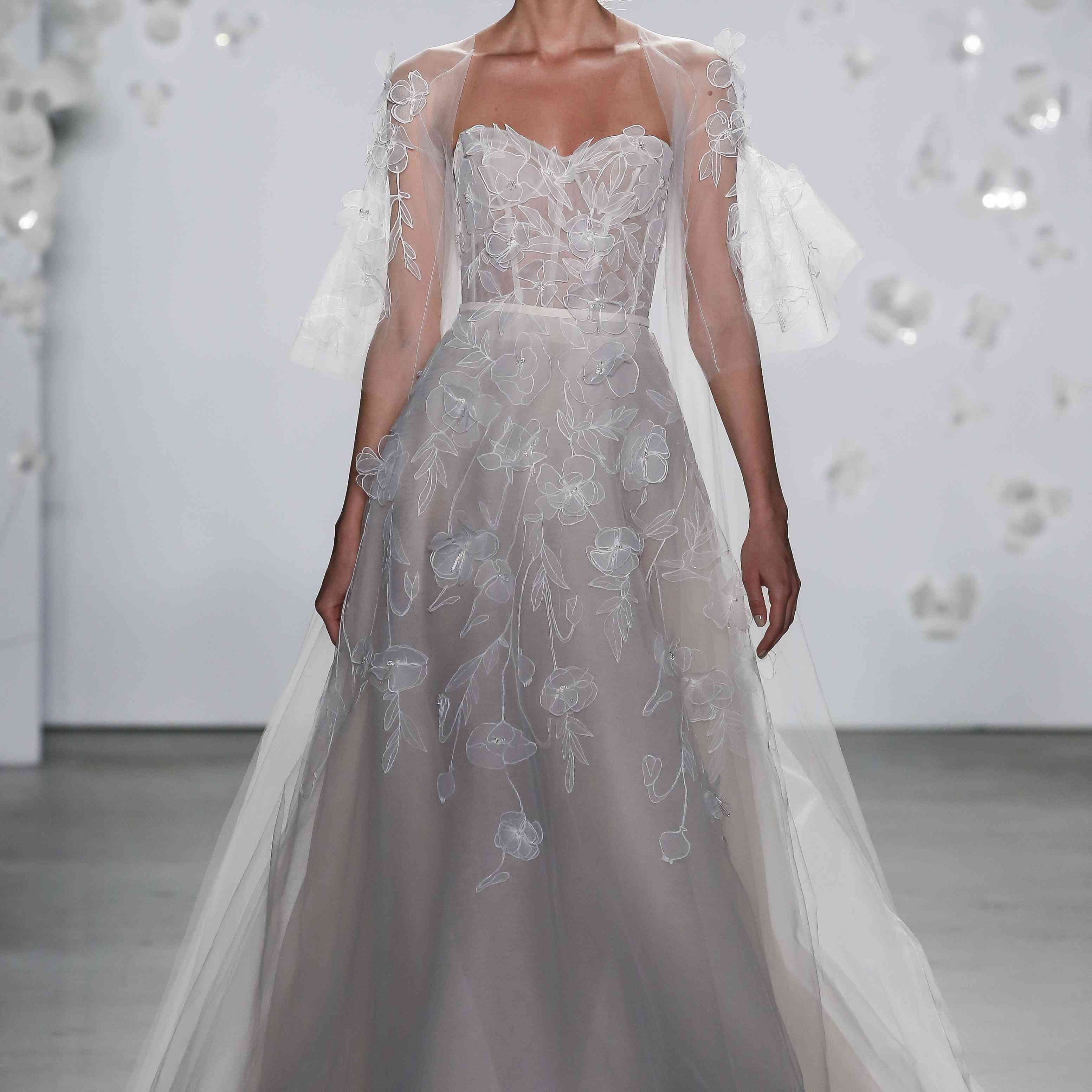 模特穿着带有花卉刺绣的薄纱a字裙和一件透明披风