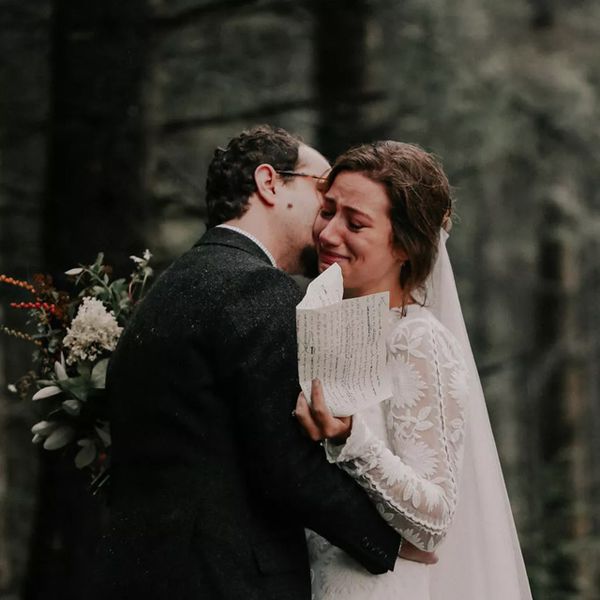 在面颊的新郎亲吻新娘，因为她得到了情感拿着手写的誓卖