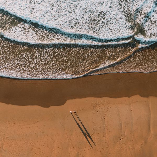 一对夫妇在海滩上的鸟瞰图”class=