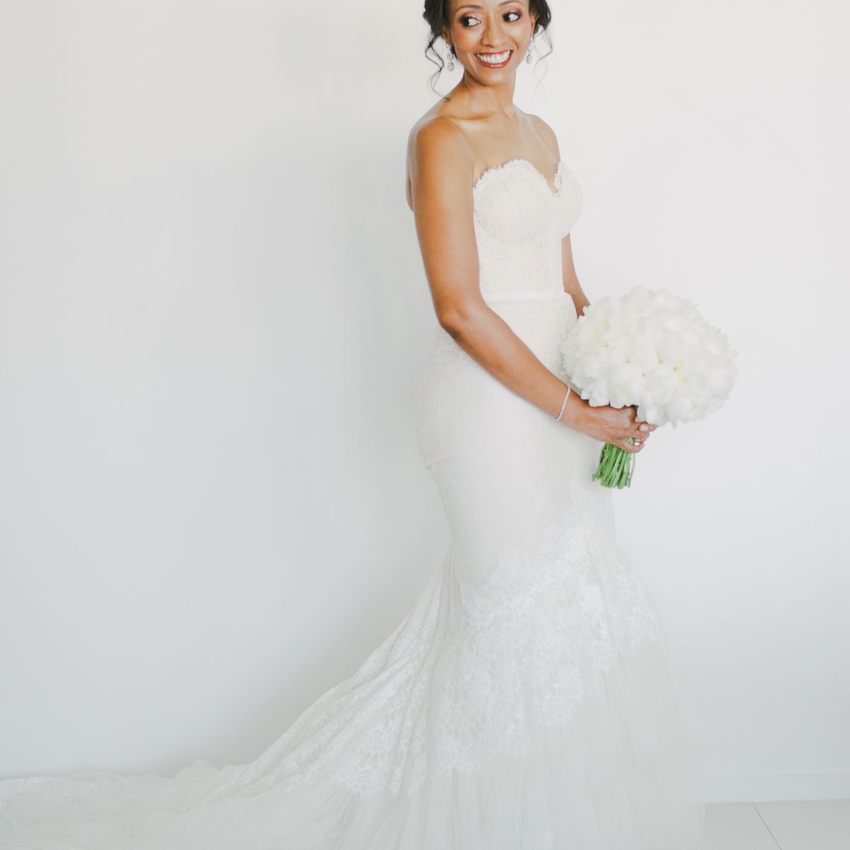 有美人鱼婚礼礼服的新娘携带白色花卉圆的花束