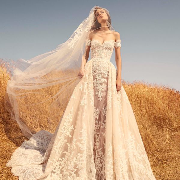 在一个脱肩外壳的模型，装饰着绣花灰白色花边贴花和匹配面纱