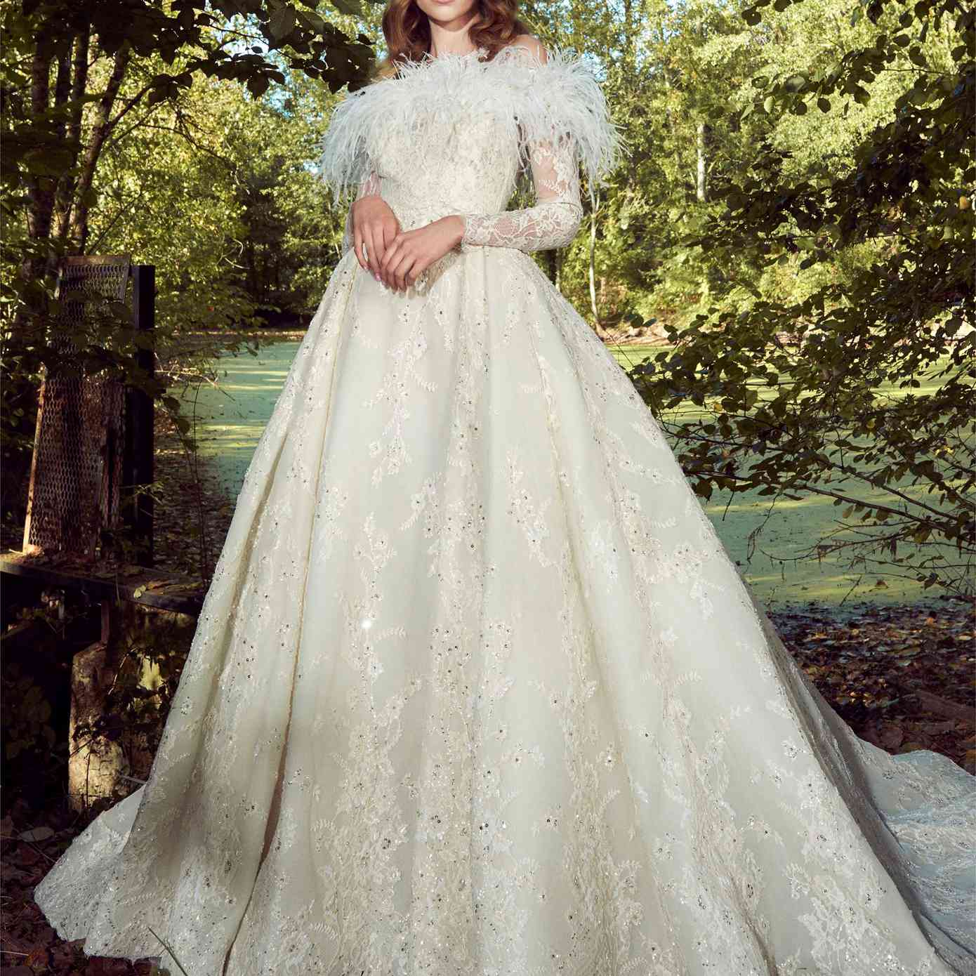 模型在一个白色的高领无袖舞会礼服和印花布亮片花卉蕾丝刺绣蕾丝长袖和羽毛套衫