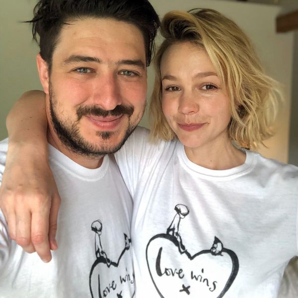 Marcus Mumford横梁在一个孪生的“爱胜利”衬衫与妻子Carey Mulligan，他搂着他的脖子