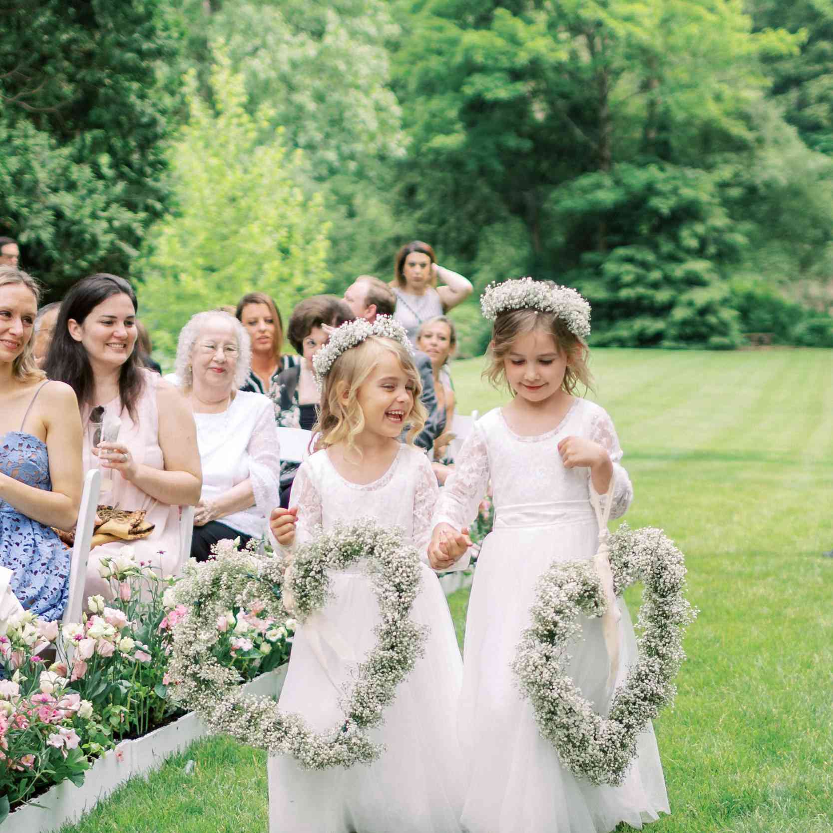 运载婴孩的呼吸心脏花圈的两个花女孩与匹配的花冠的过道