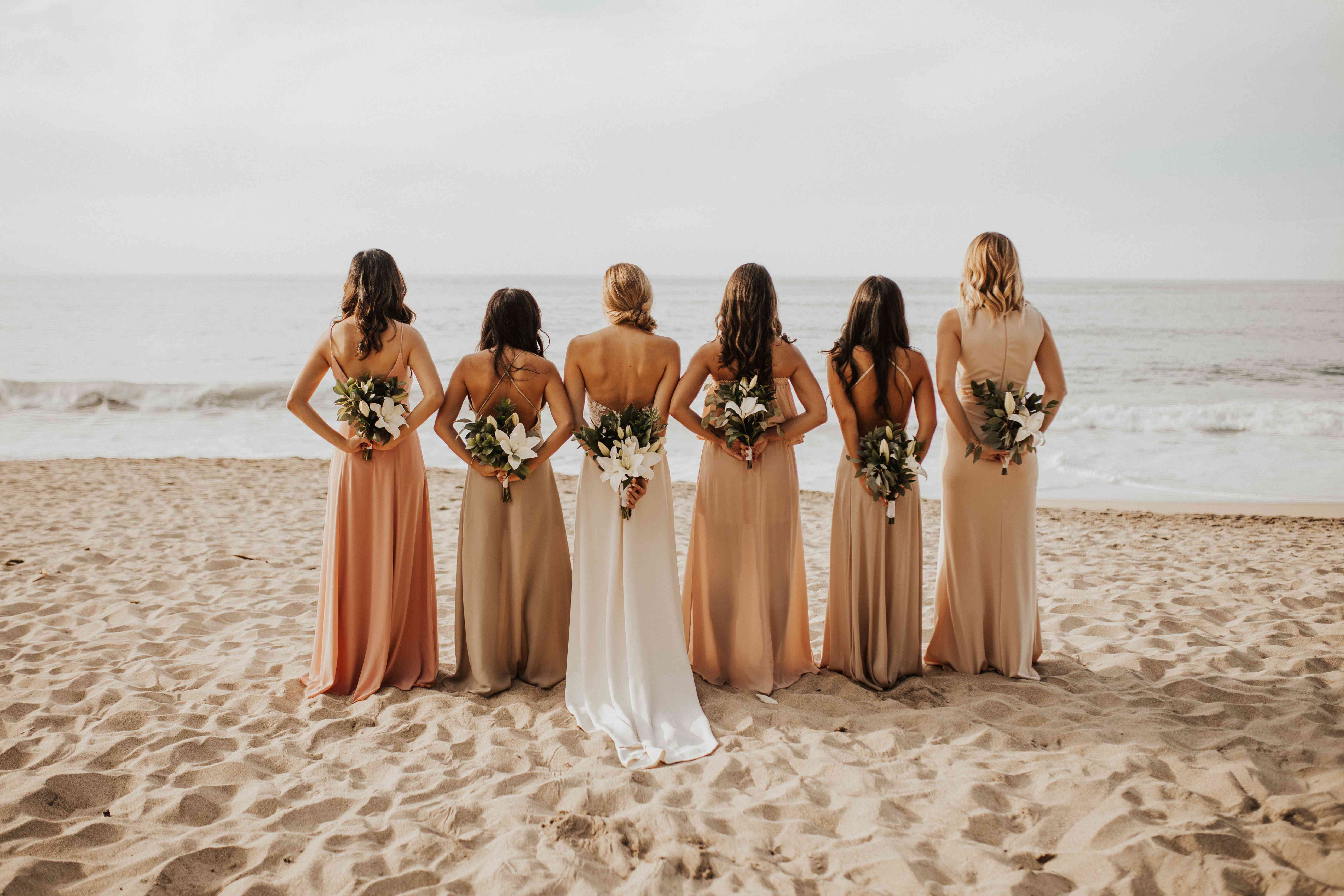 看在海洋的伴娘和新娘有在他们的背后的花束的