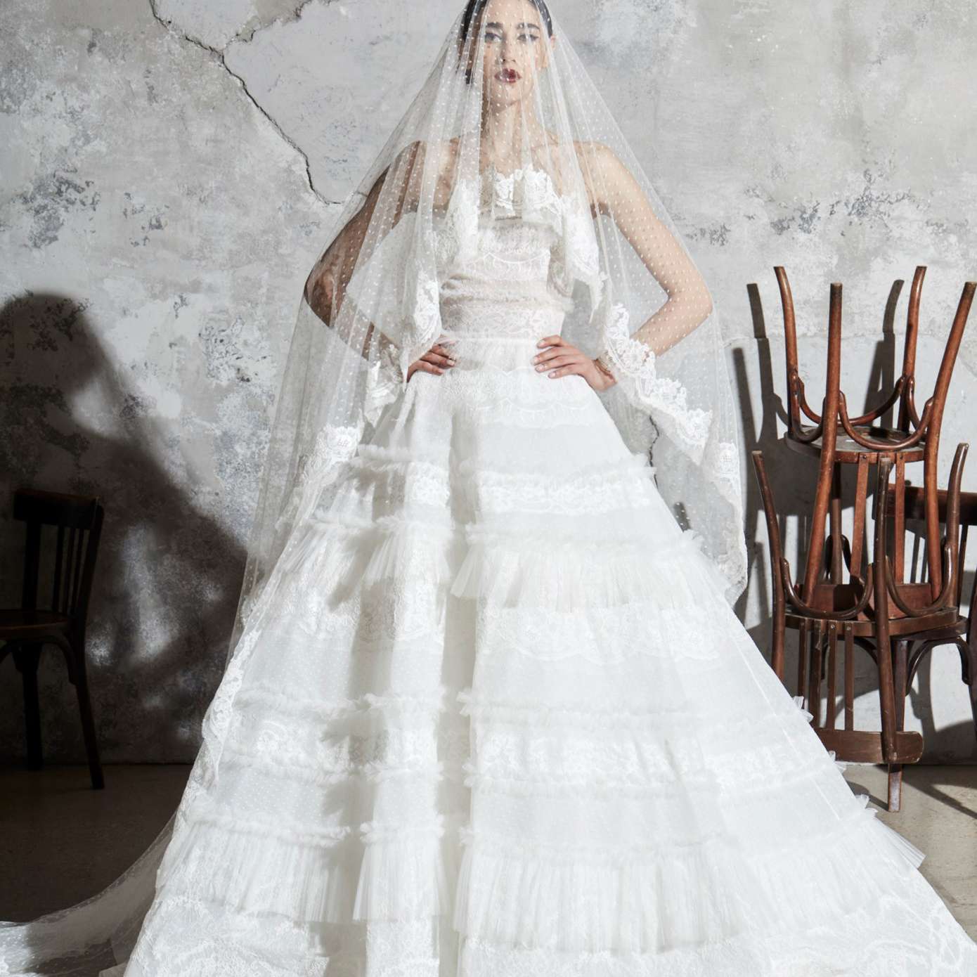 模型在无肩带蕾丝与薄纱舞会礼服的褶薄纱褶边和花边的点缀色面纱