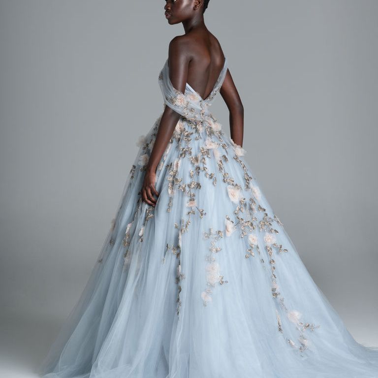 模特在蓝色舞会礼服与不对称的露肩领口和3D花卉刺绣