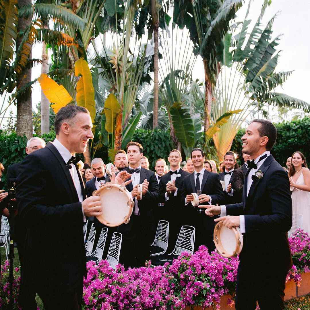 在他们的婚礼上演奏手鼓的两把新郎，当客人观看和玩耍