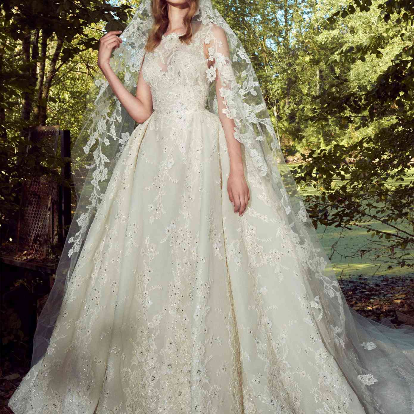 模型在一个白色的高领无袖舞会礼服和印花布亮片花卉蕾丝刺绣与匹配的面纱