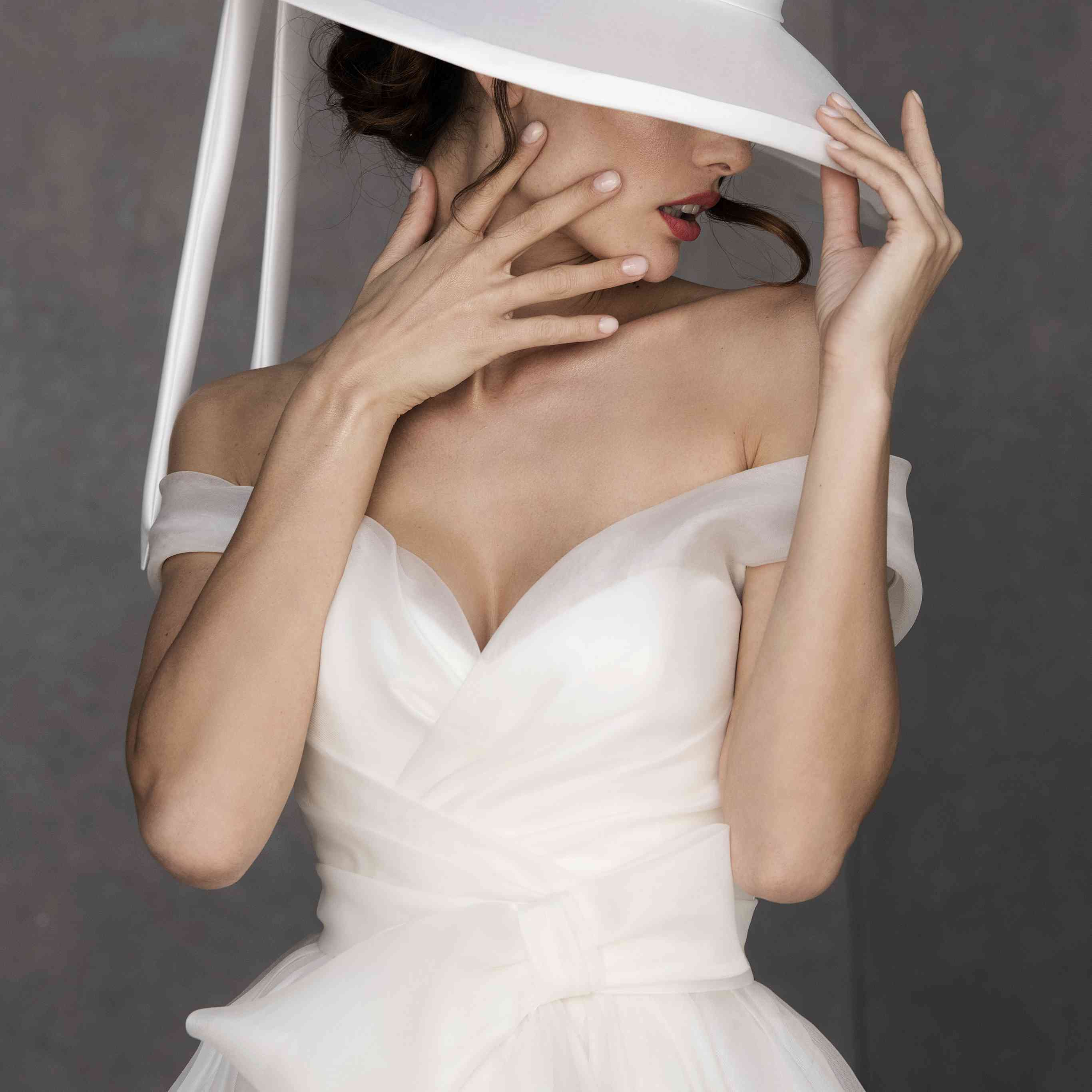 与大蝴蝶结细节身穿场外的肩总结效果薄纱长礼服型号宽边白帽子