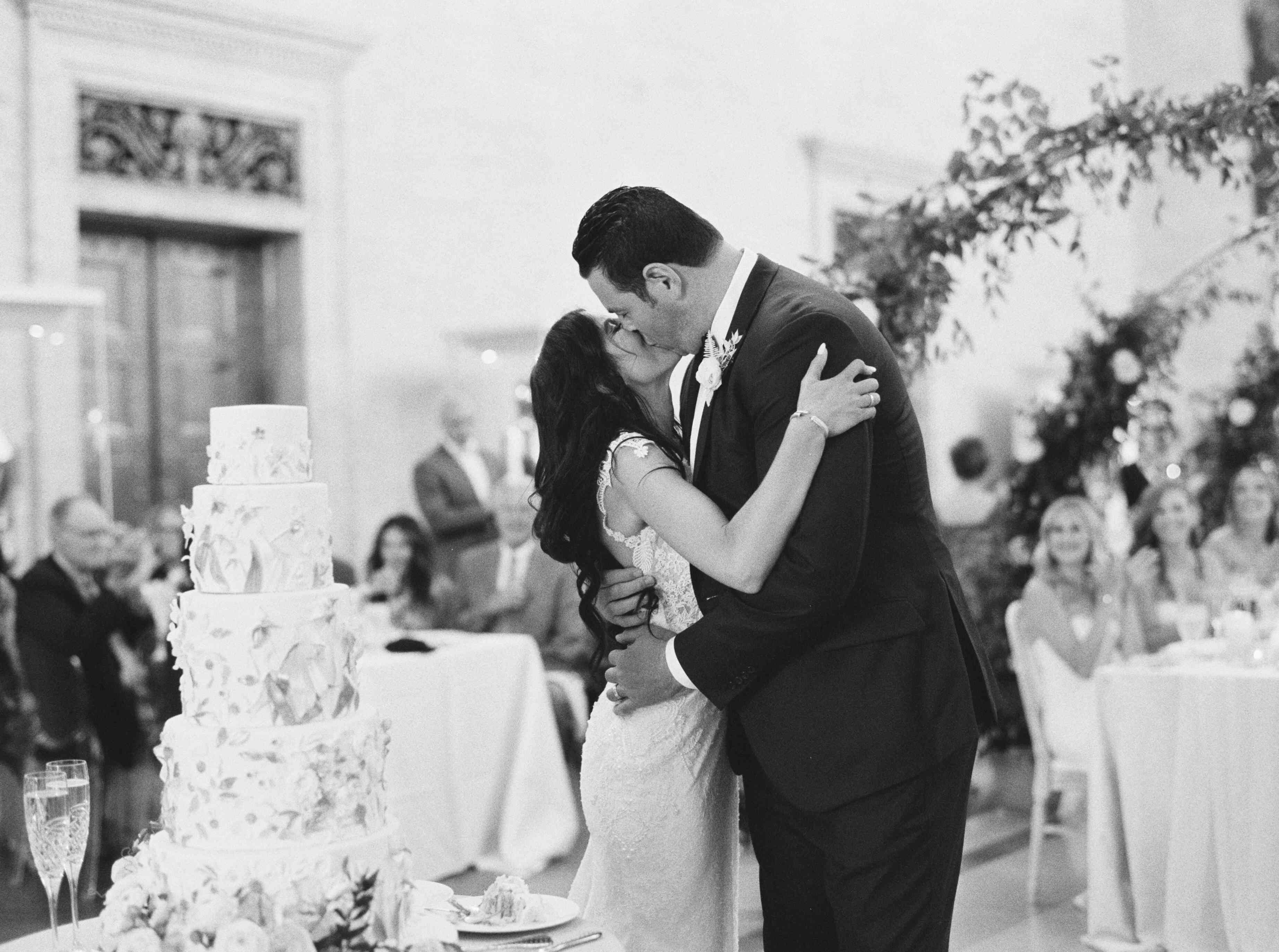 削减他们的结婚蛋糕后，夫妇亲吻